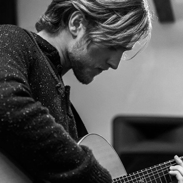 A man is playing an acoustic guitar in a black and white photo.