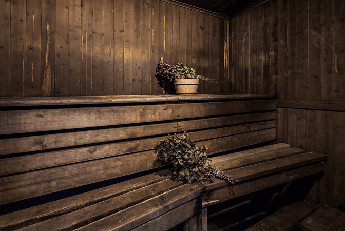 A wooden bench in a sauna with a pot of plants on it.