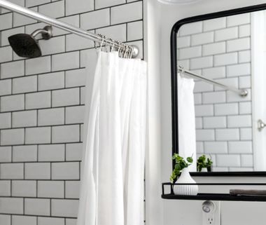A bathroom with a shower curtain and a mirror