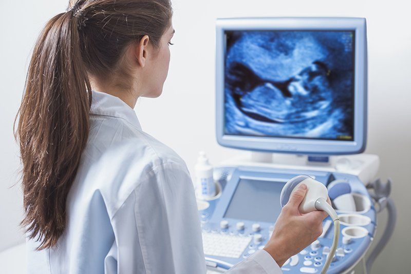 A woman is looking at an ultrasound of a baby on a computer screen.