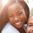A man and a woman are hugging each other and smiling for the camera.