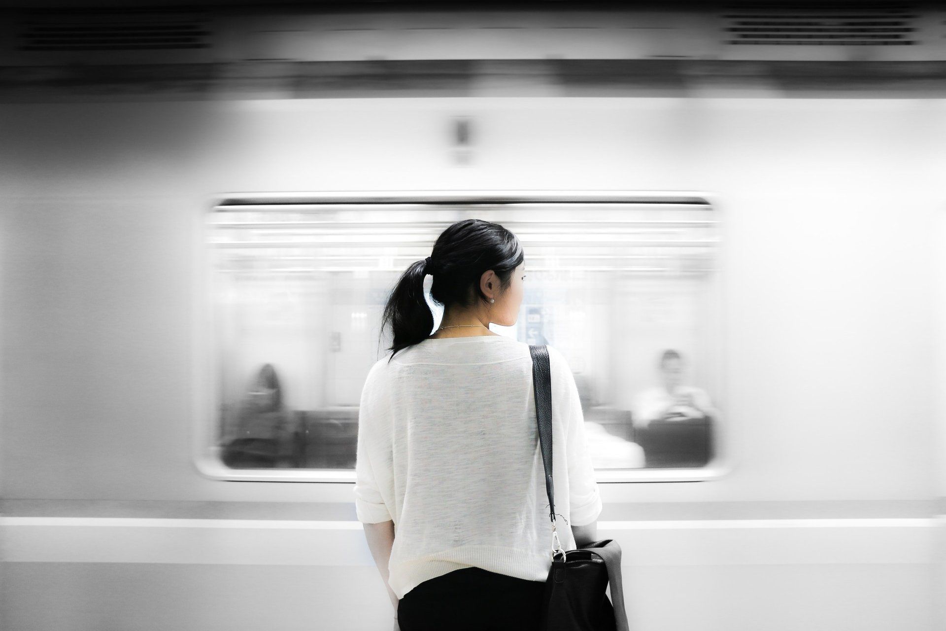 A woman is standing in front of a train looking out the window.