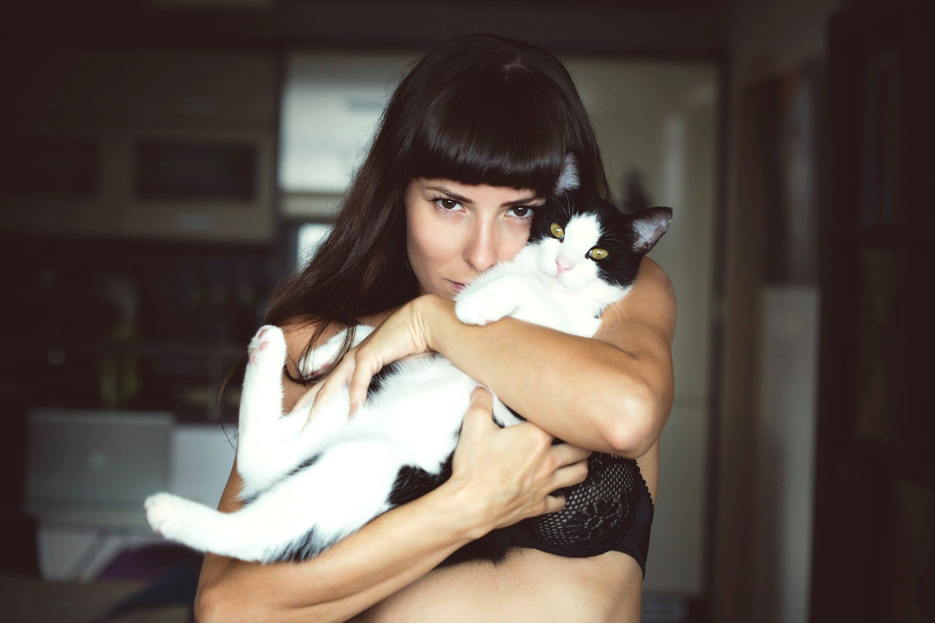 A woman is holding a black and white cat