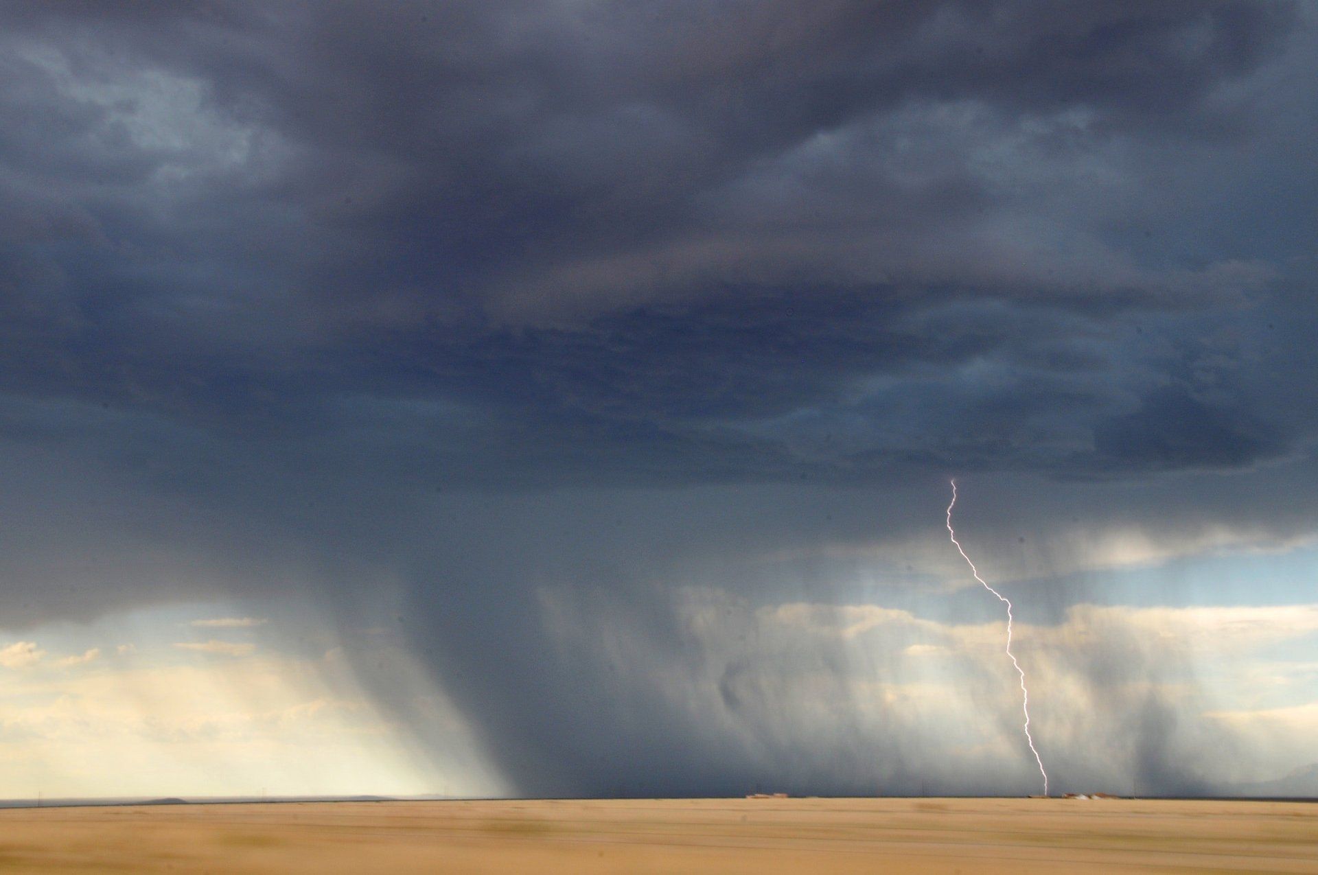 There is a lightning bolt in the sky over a field.