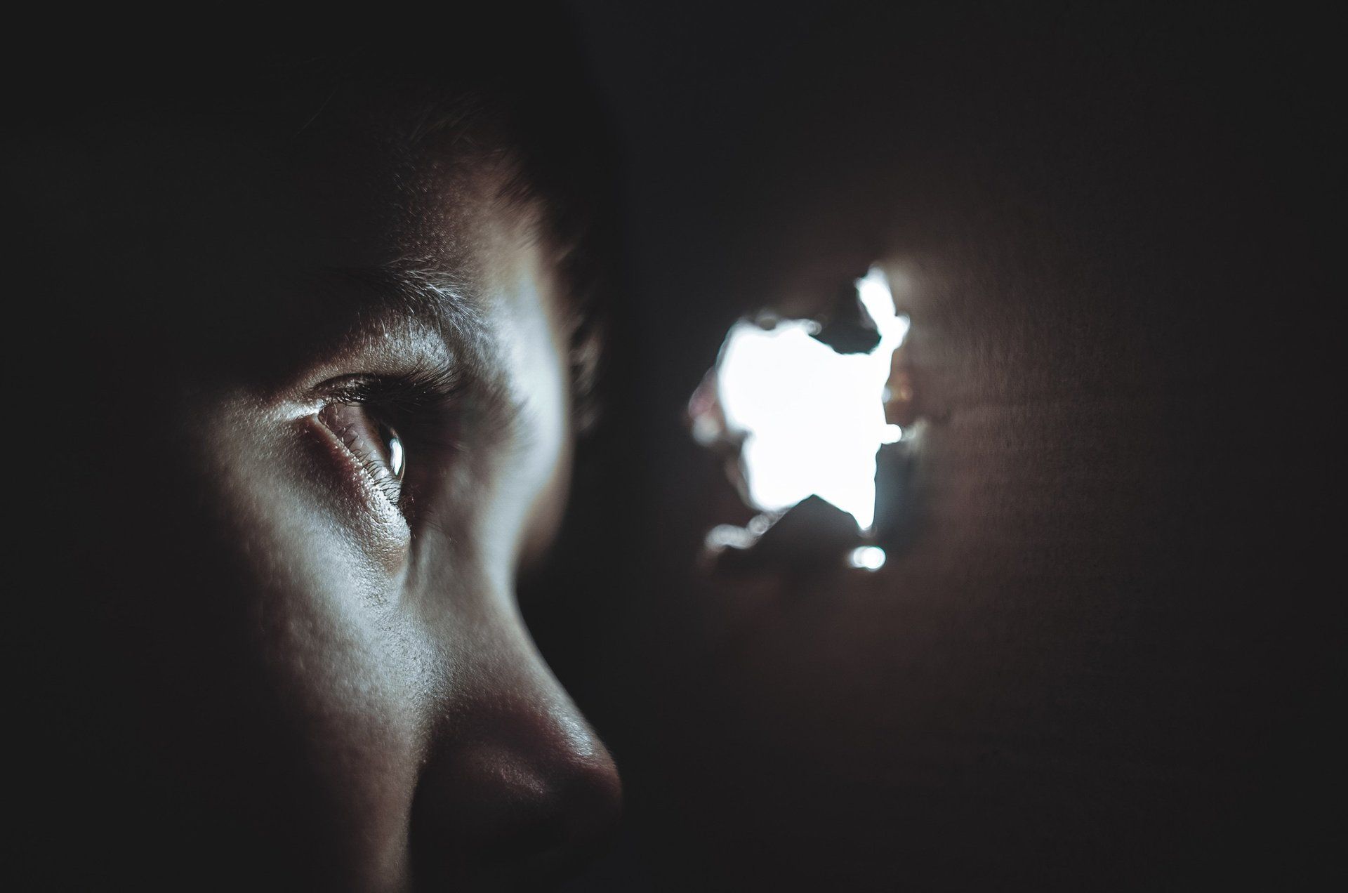 A close up of a person 's eye looking through a hole in a wall.