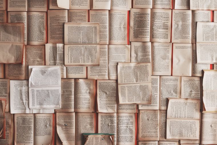 A photograph of many books open to pages full of words.
