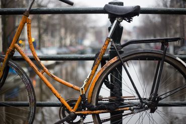 A bicycle is chained to a railing on a bridge.