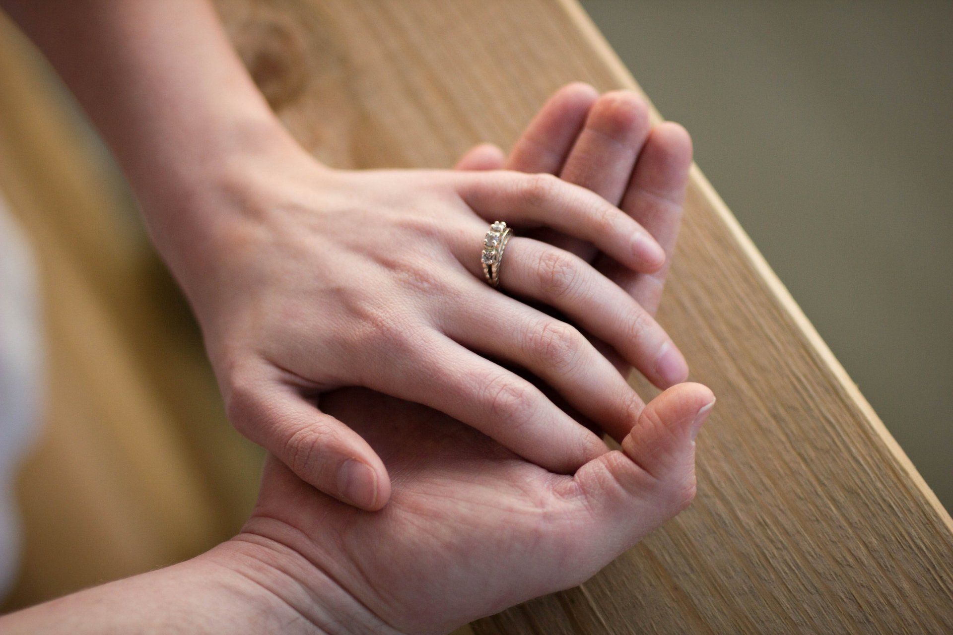 A woman wearing a wedding ring is holding a man 's hand.