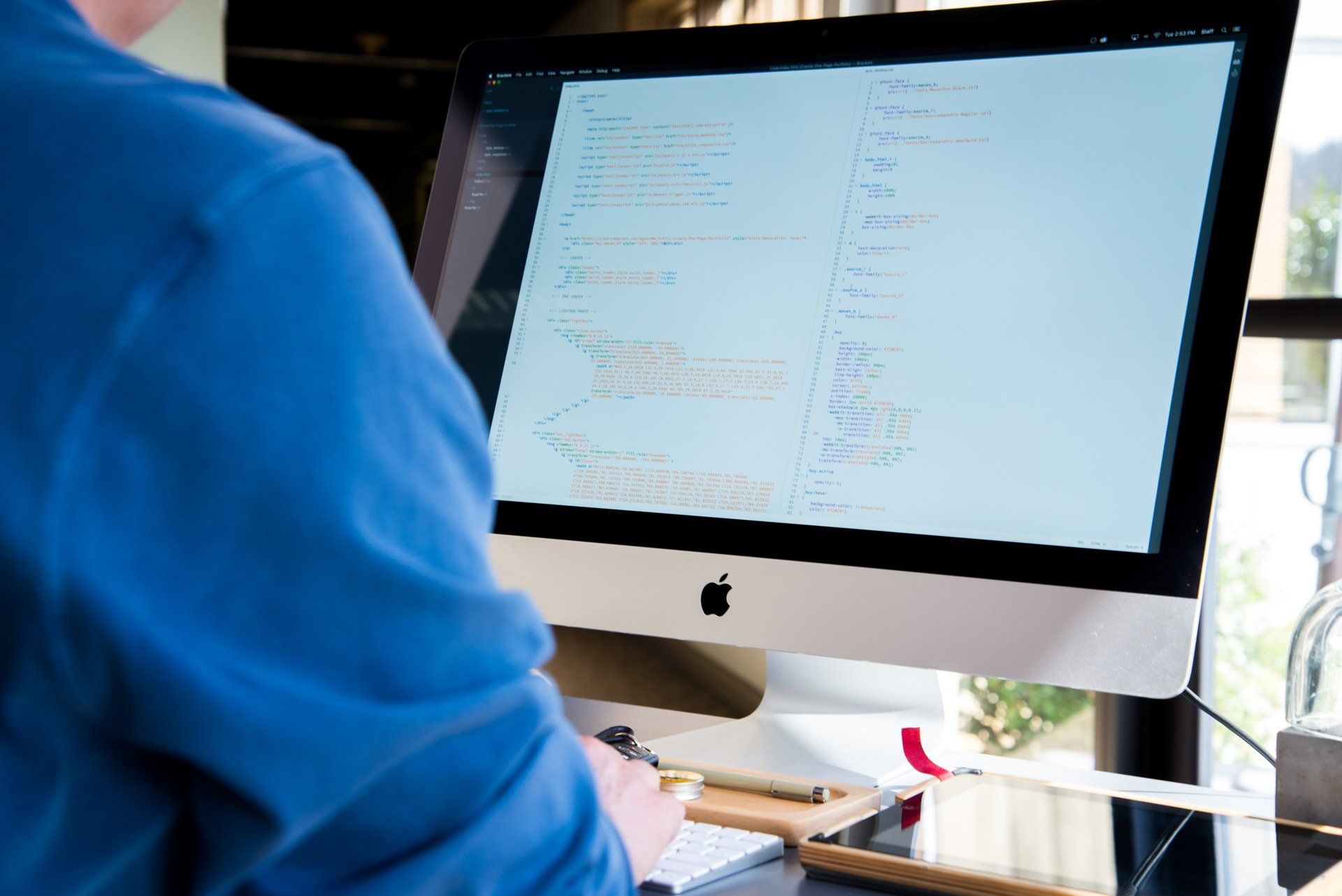 A man in a blue shirt is coding.