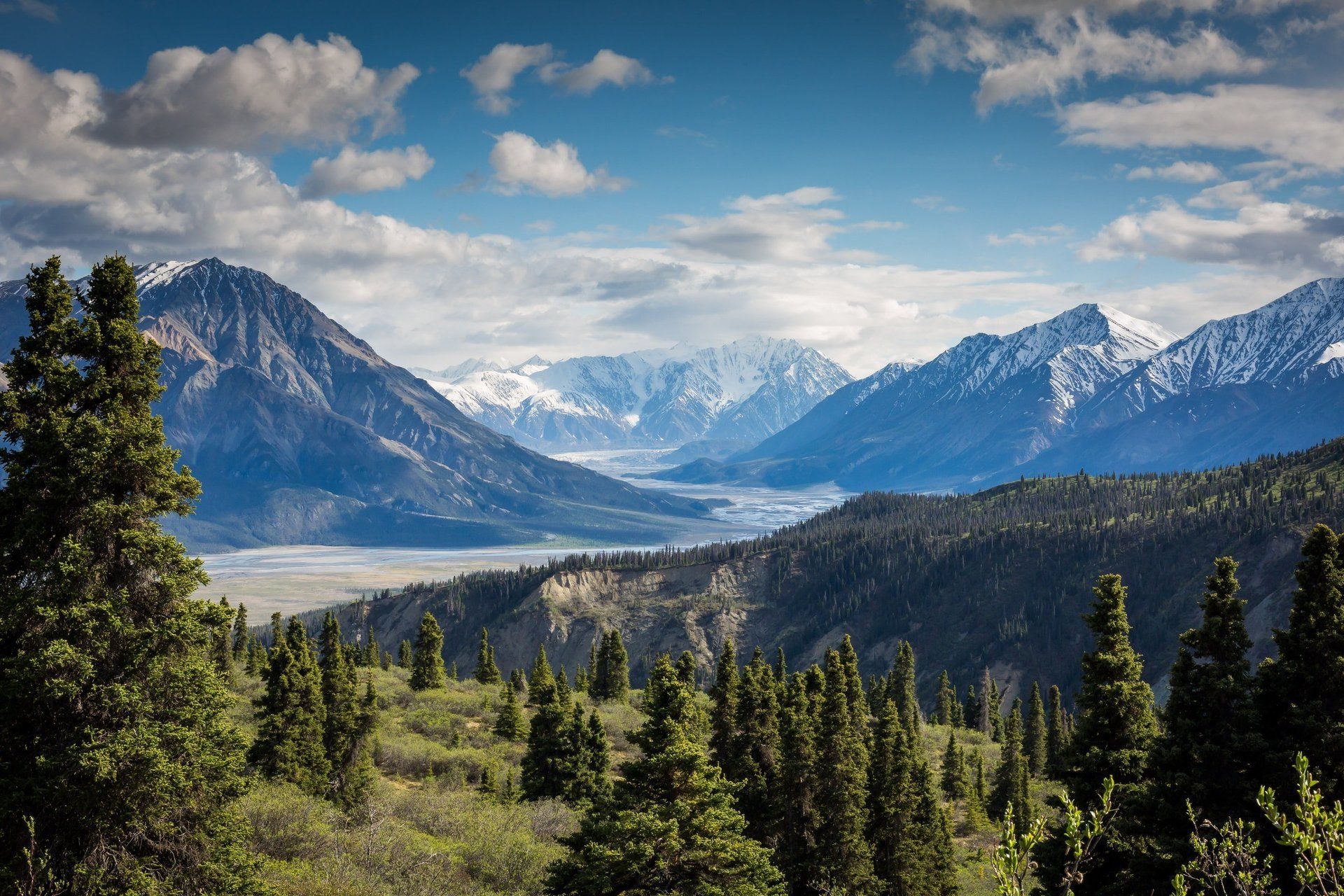 A view of a valley with mountains in the background and trees in the foreground.