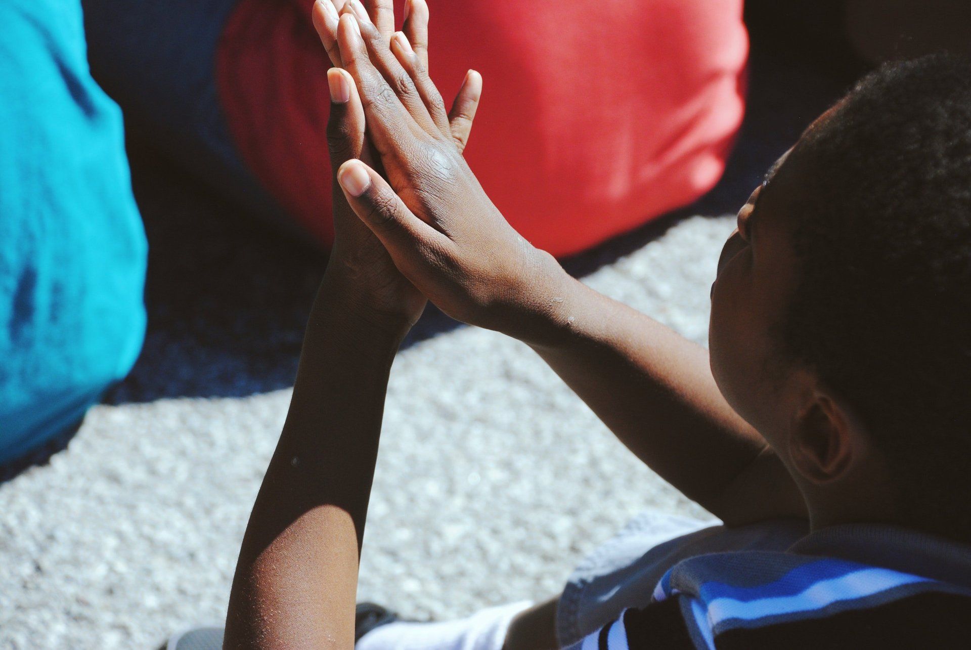 A young boy is giving another child a high five while sitting on the ground.