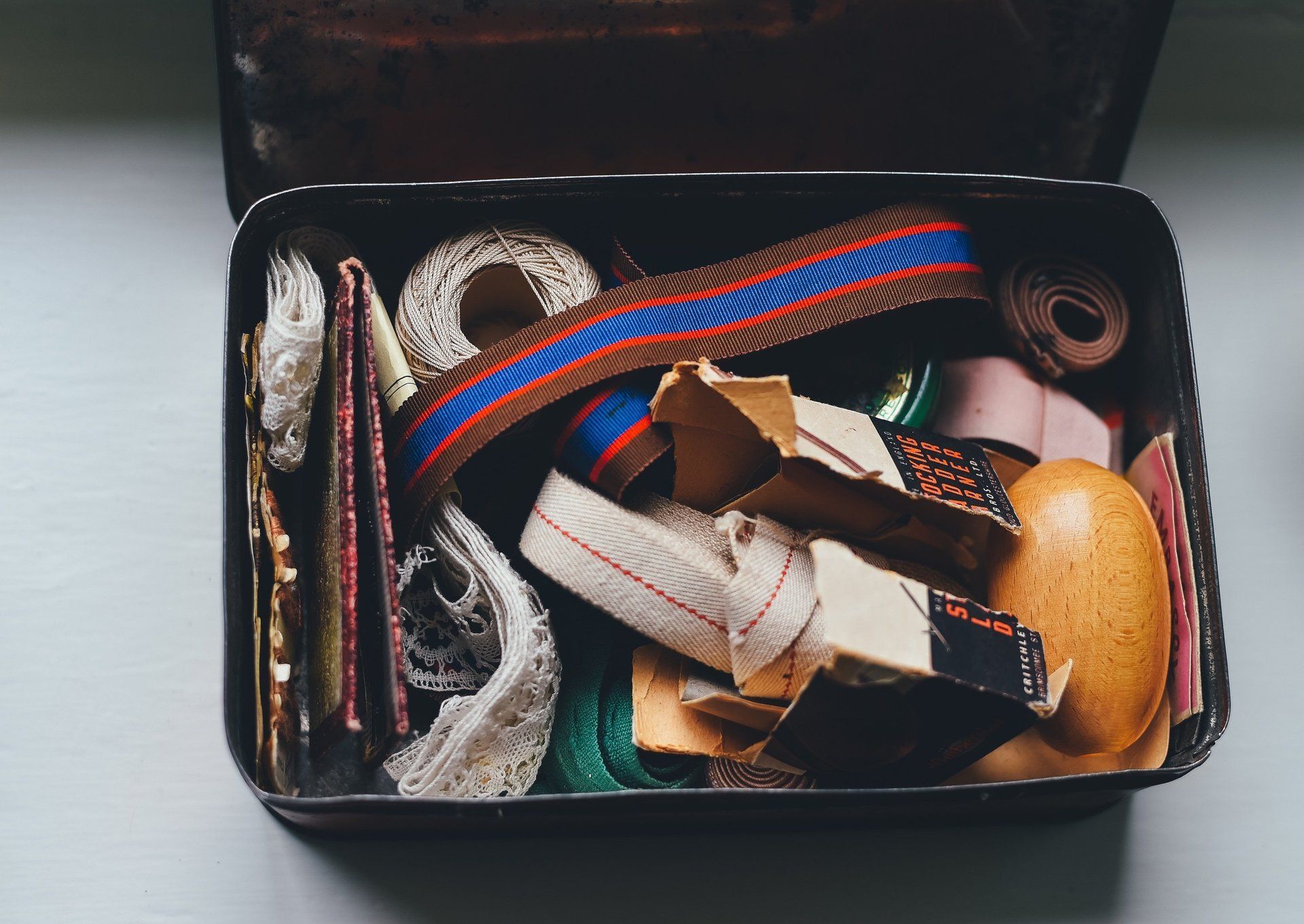 A tin filled with ribbons , tape , and other items