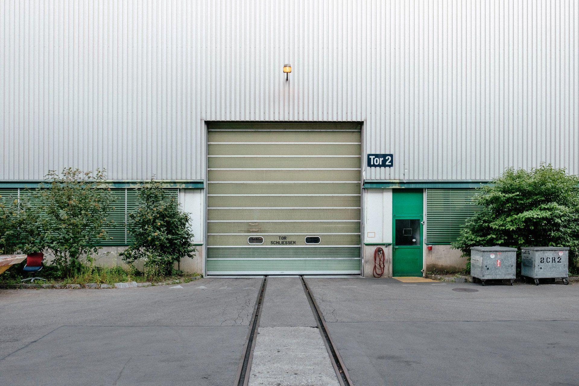 A large warehouse with a green door and a large garage door.