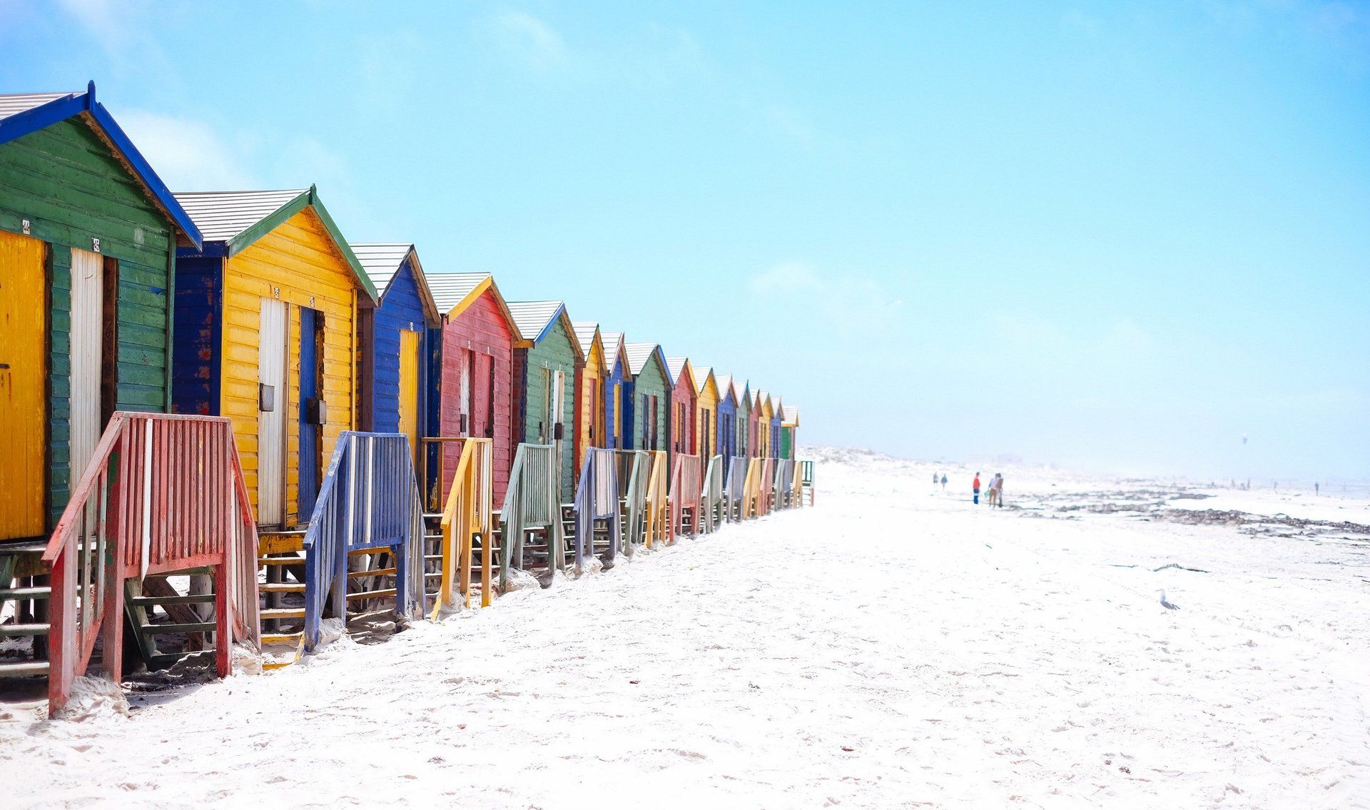 Une rangée de cabines de plage colorées sur une plage.
