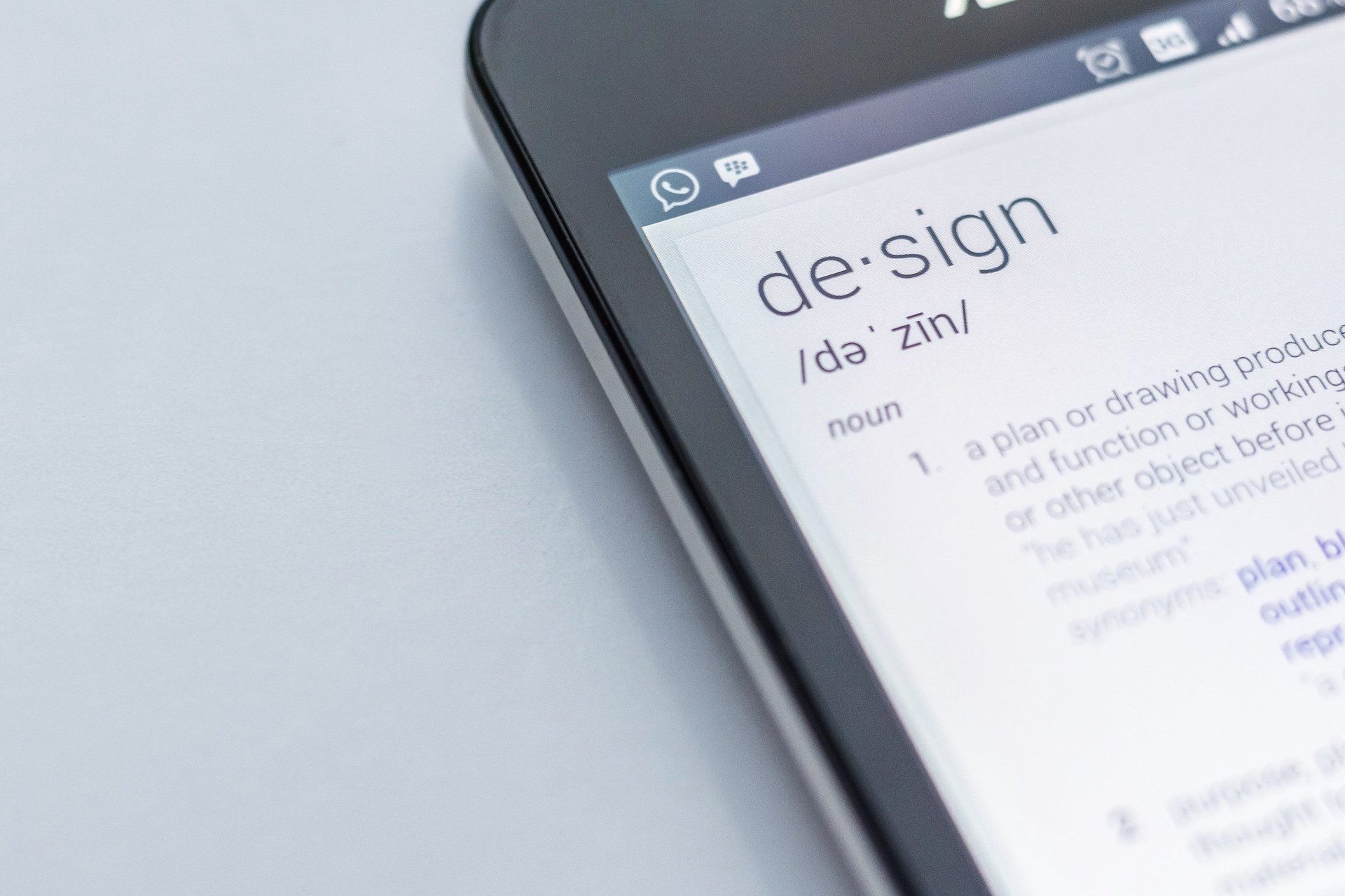 A close up of a cell phone with the word design on the screen.