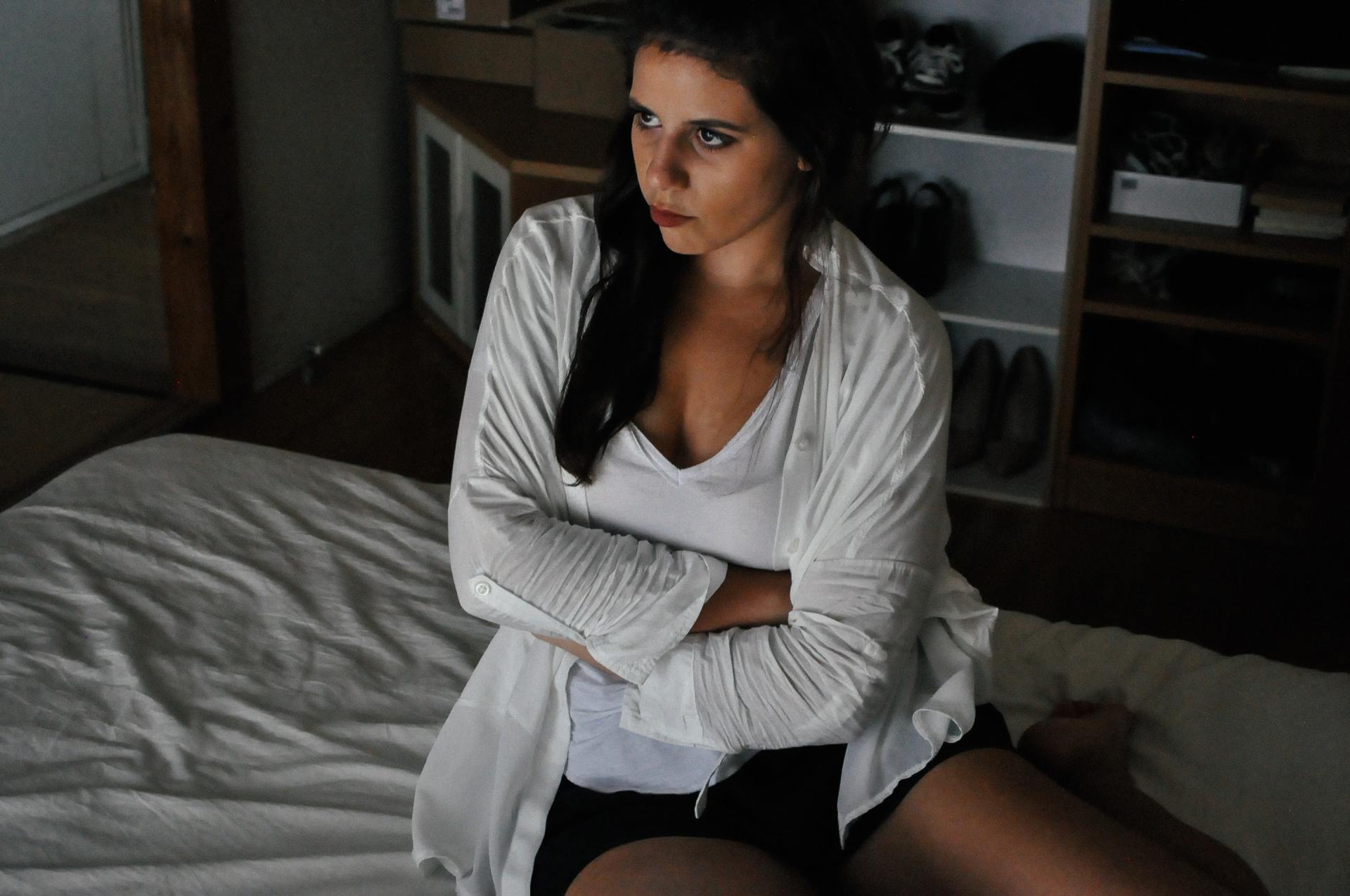 A woman is sitting on a bed with her arms crossed.