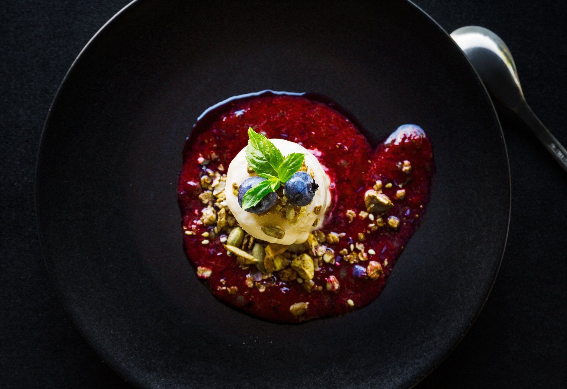 A black plate topped with a dessert and a spoon