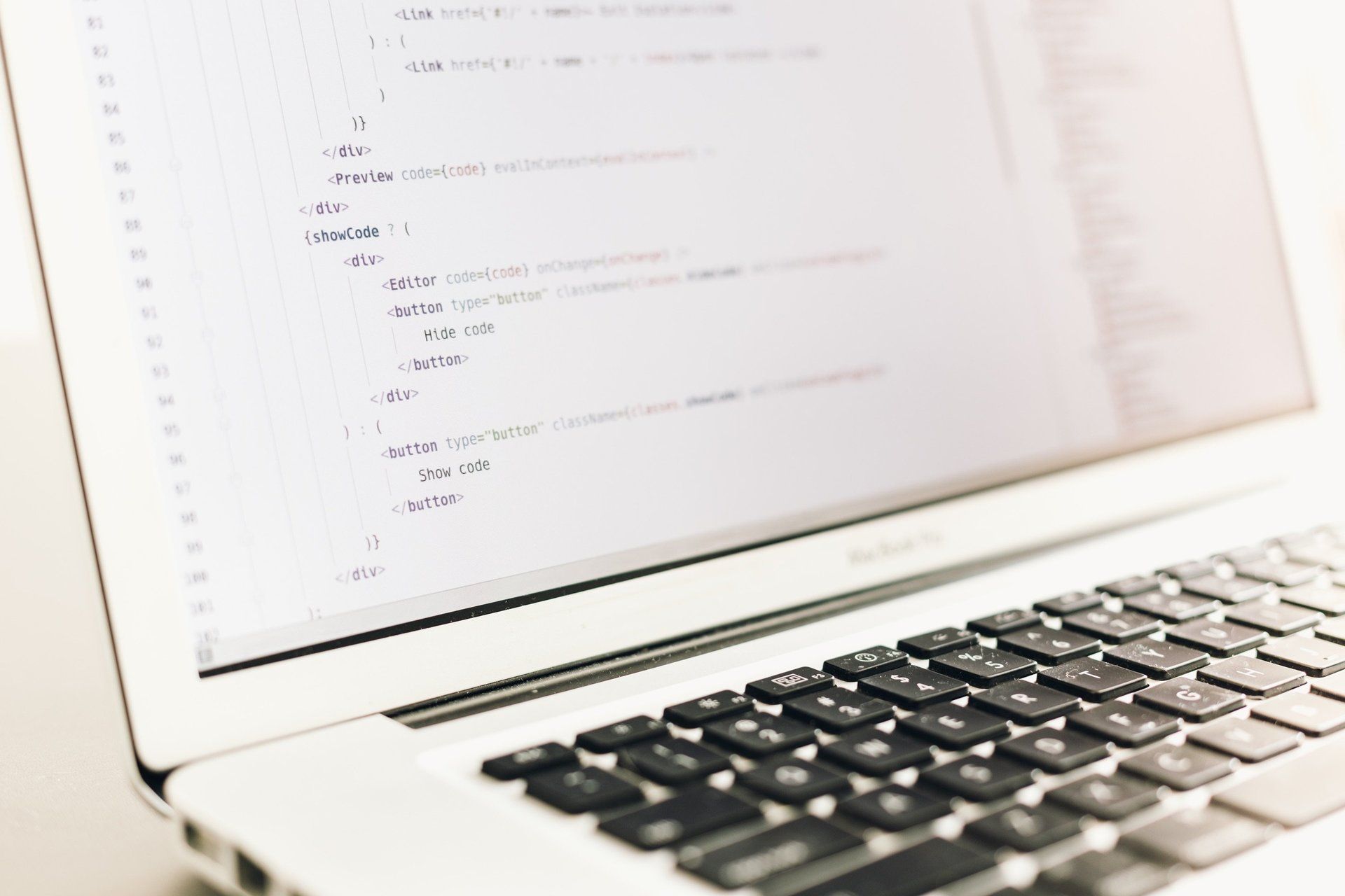 Laptop screen showing code, with a black keyboard in the foreground
