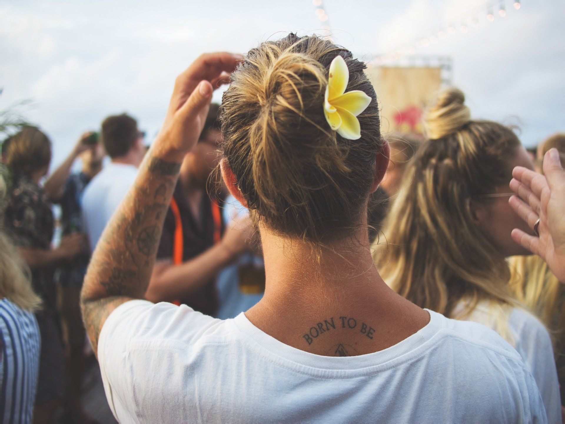 A woman with a flower in her hair has a tattoo on her back.