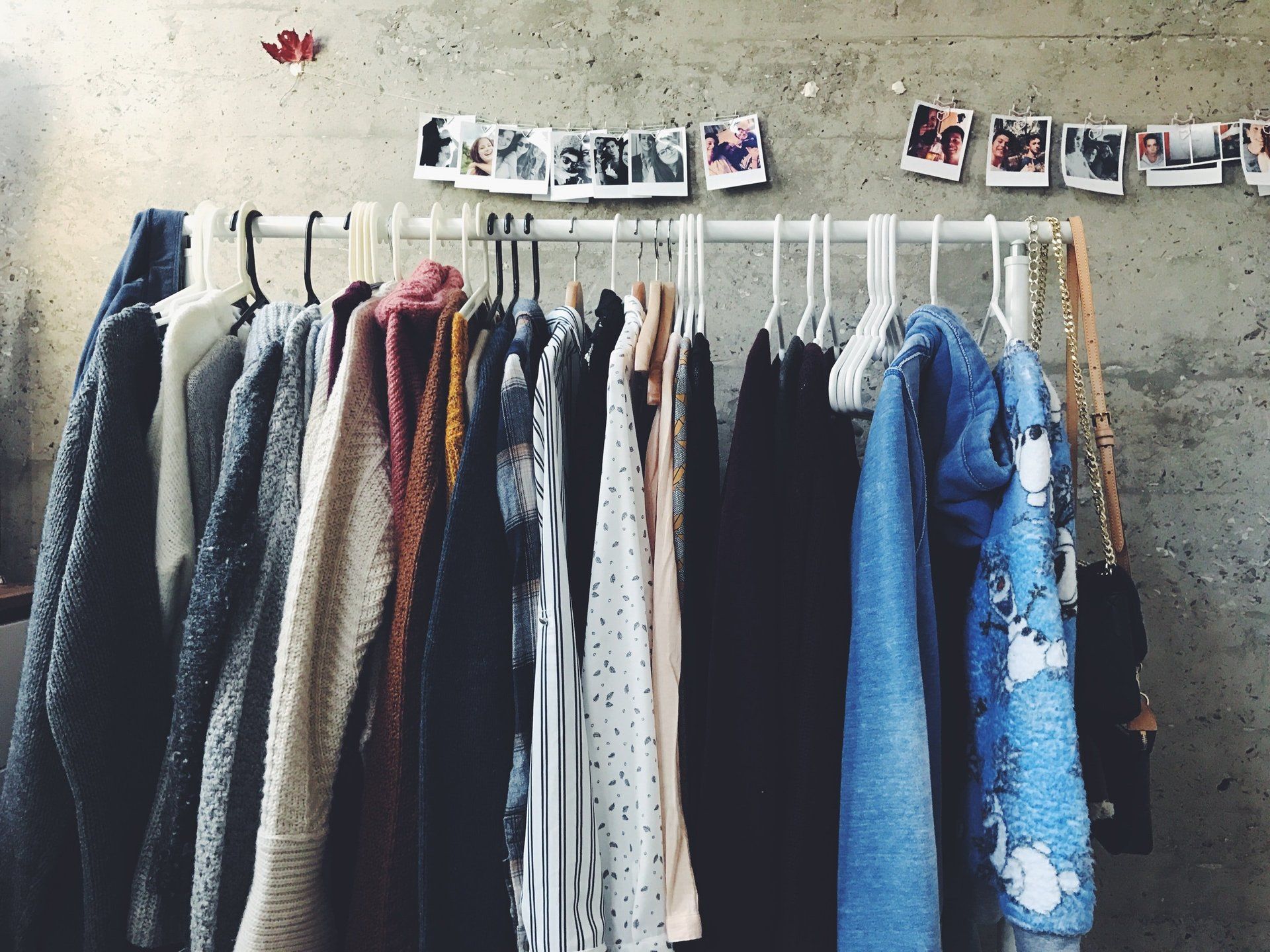 Clothes hanging on a rack with pictures on the wall behind them
