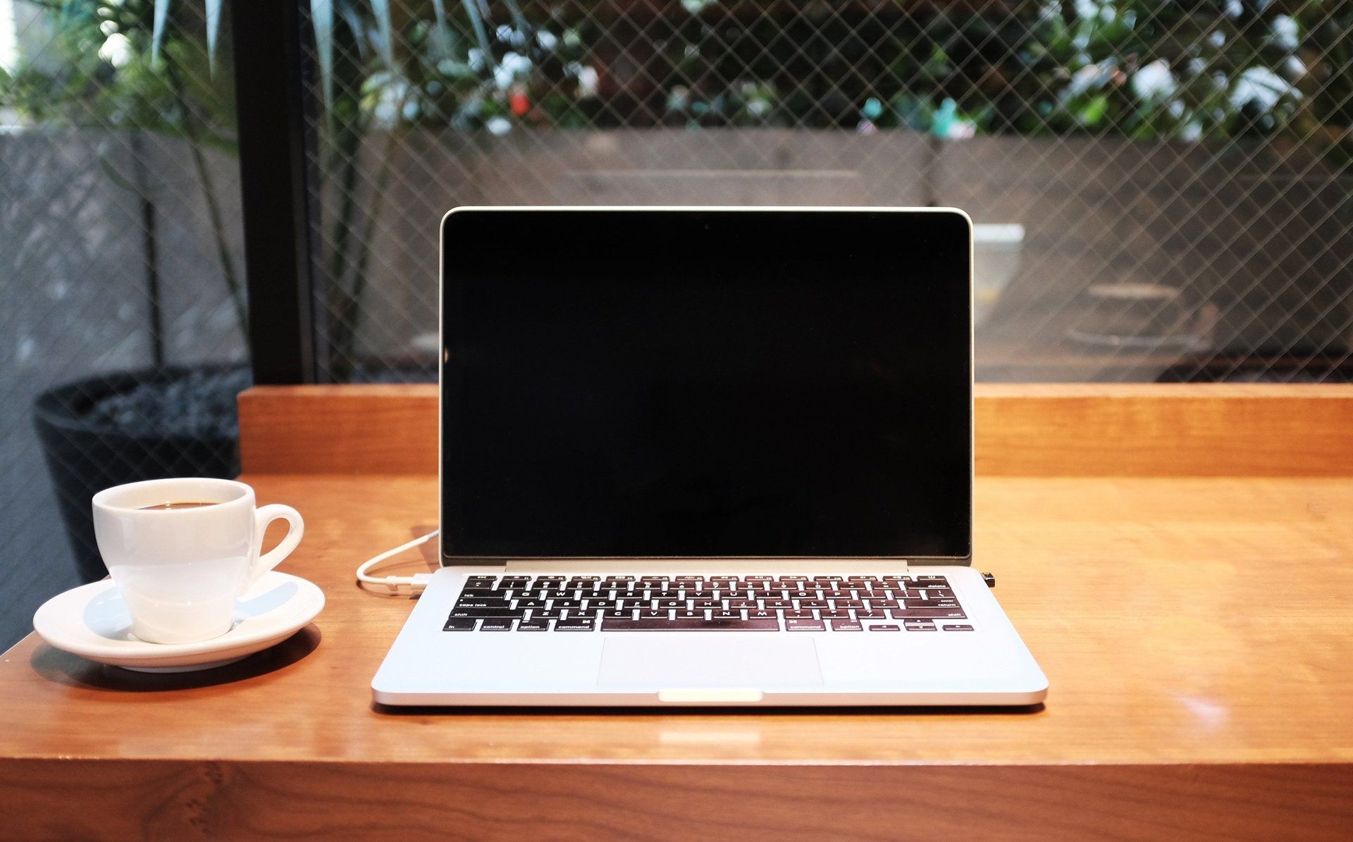 A laptop computer is sitting on a wooden table next to a cup of coffee.