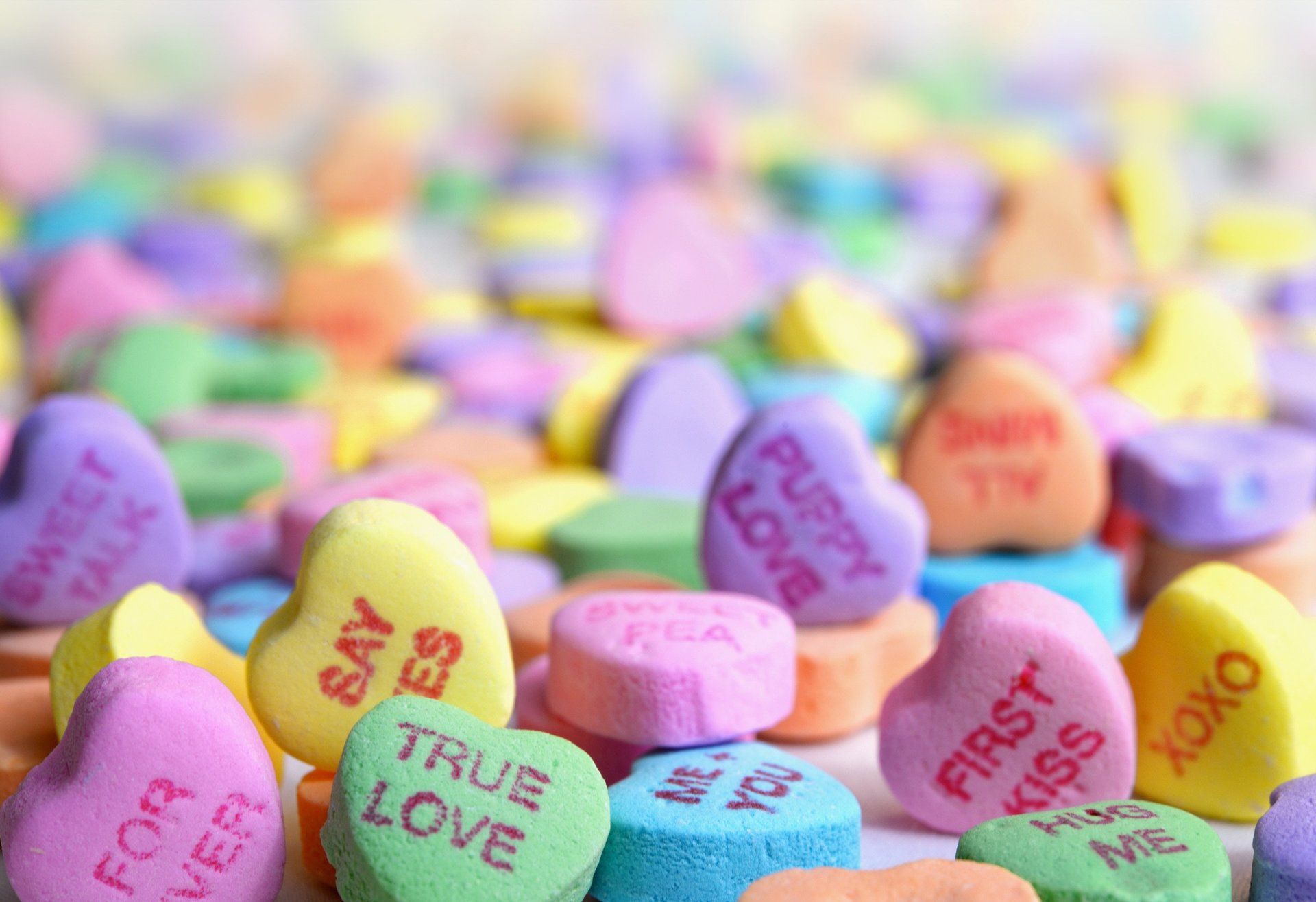 A bunch of colorful candy hearts with messages on them