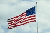 An american flag is flying in the wind against a cloudy sky