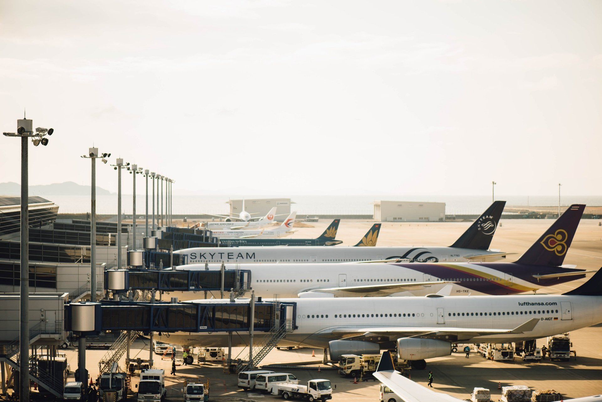 Airplanes docked at an airport terminal, with jet bridges connected. Bright, sunny day.