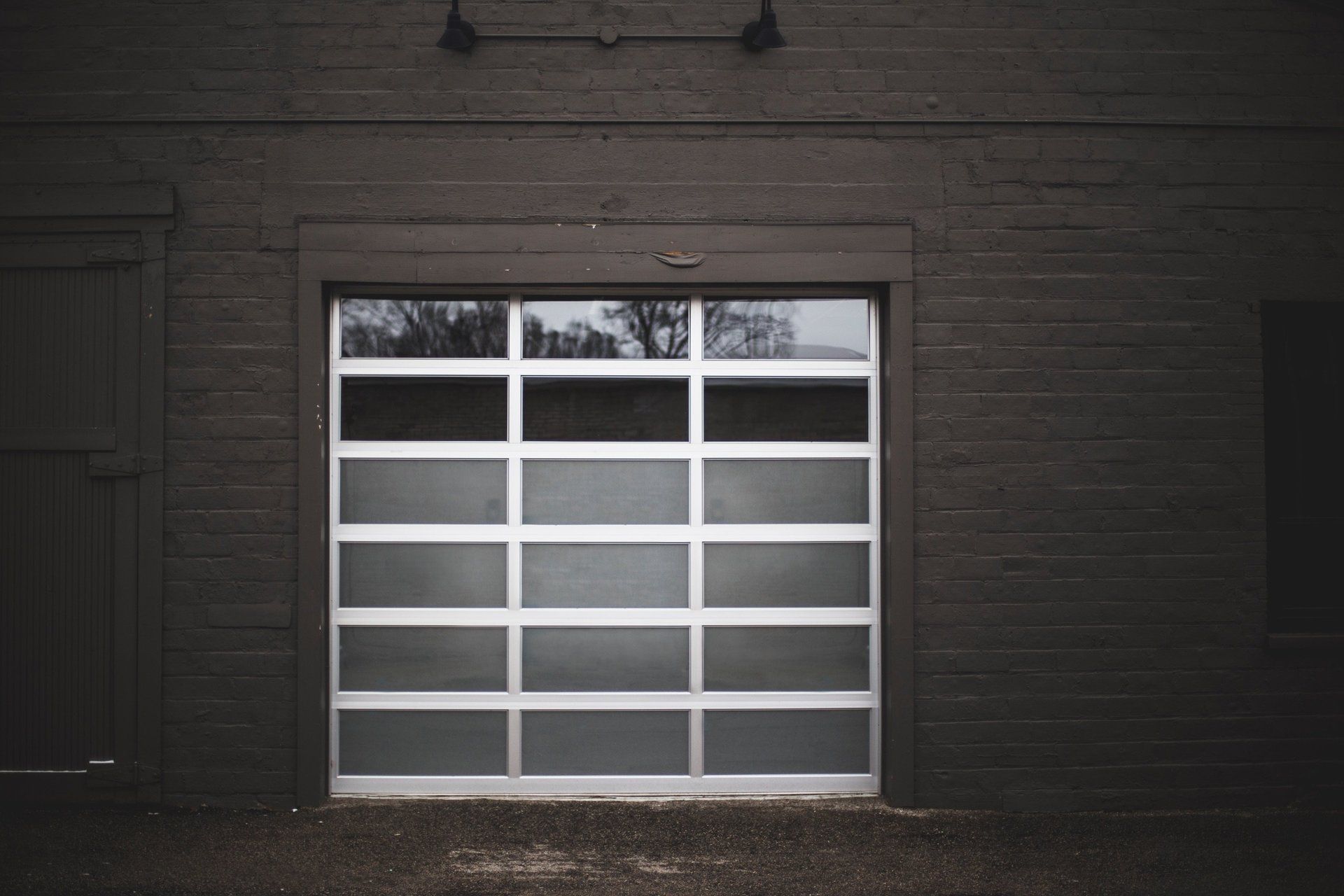 A black brick building with a white garage door.