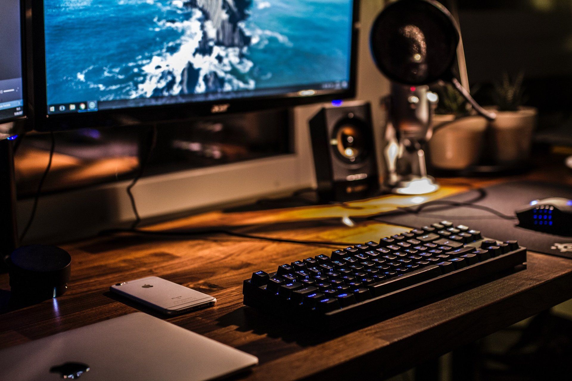 A computer monitor and keyboard are on a wooden desk.
