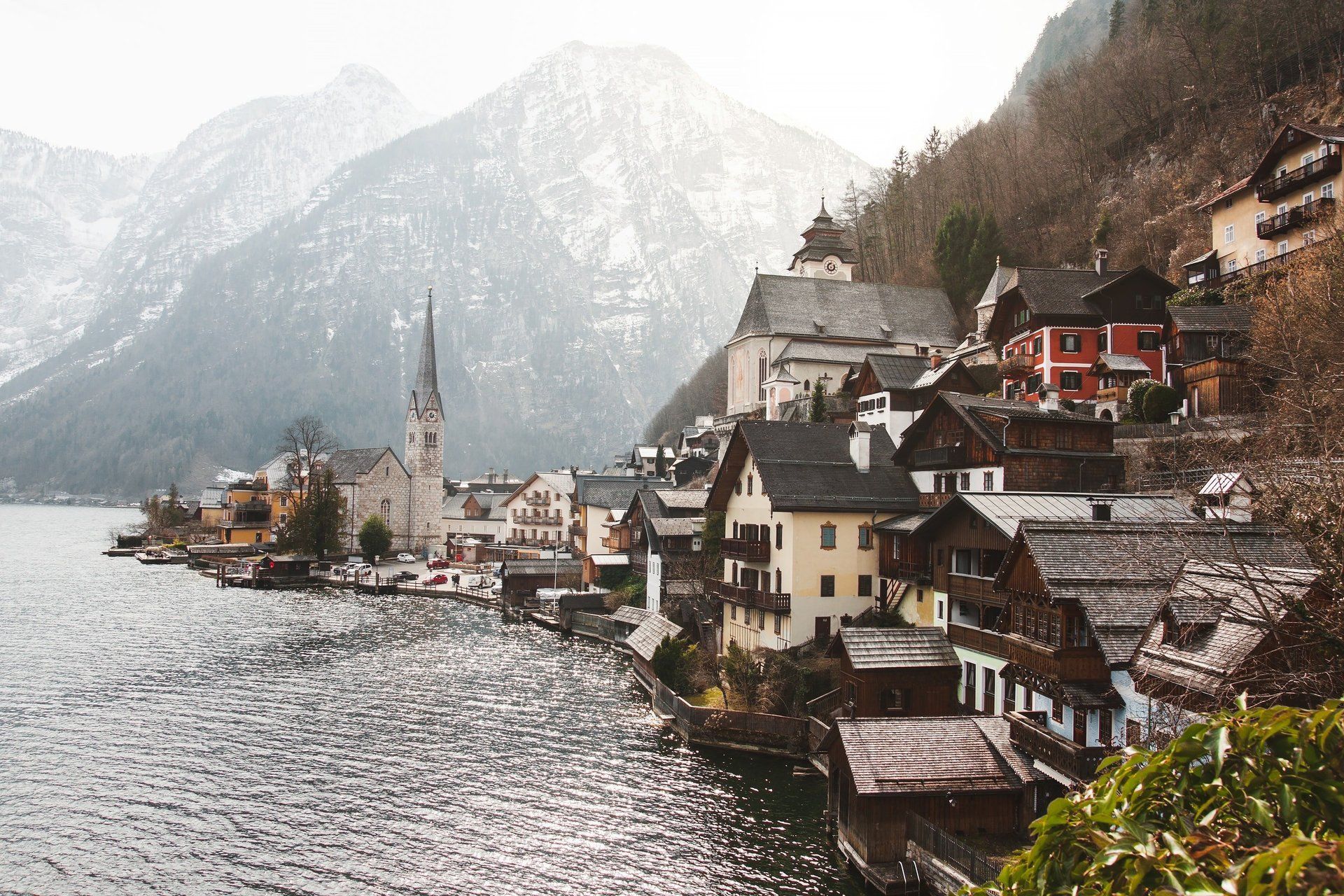 Verschneites Dorf am See mit Kirche und Häusern neben einem Berg
