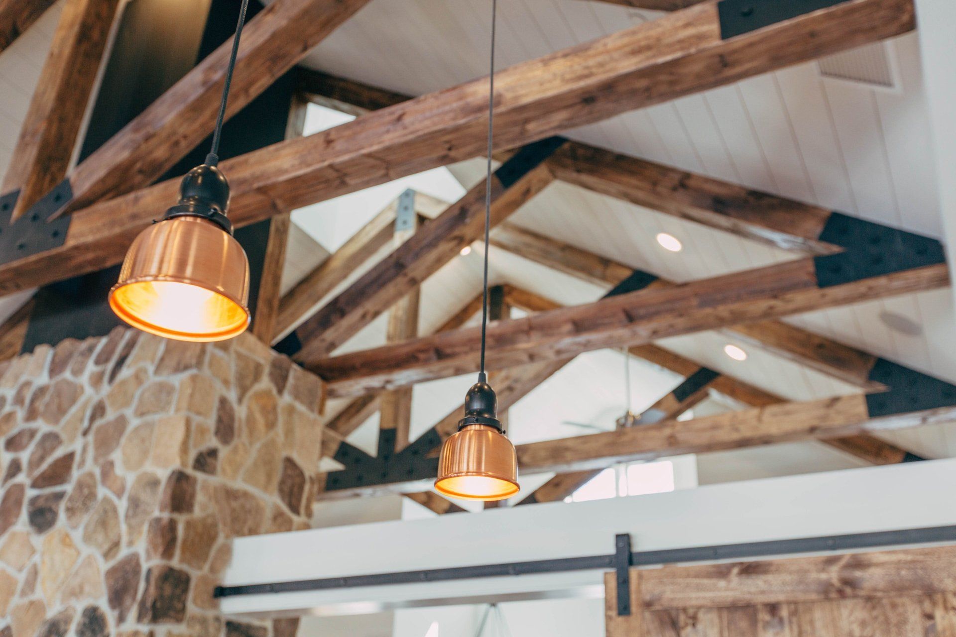 A ceiling with wooden beams and lamps hanging from it.