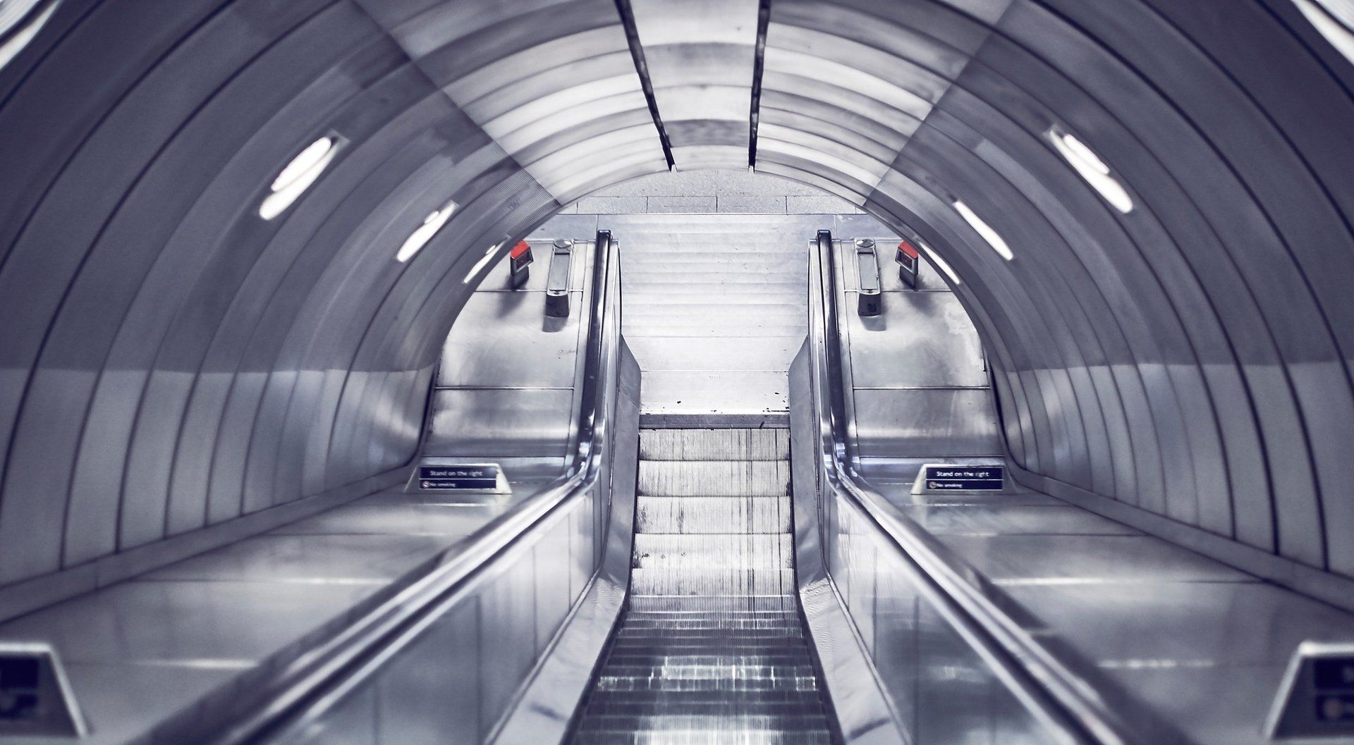 A black and white photo of an escalator in a subway station.