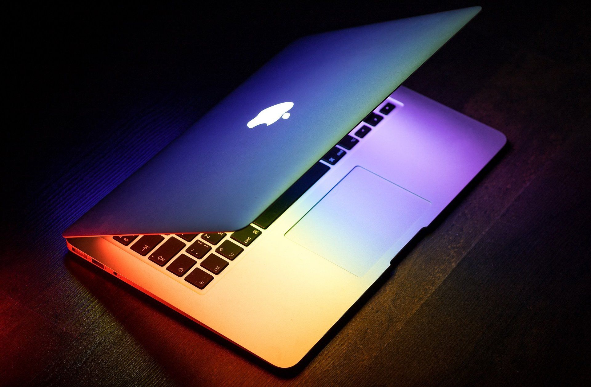 Una computadora portátil Apple con los colores del arco iris está abierta sobre una mesa