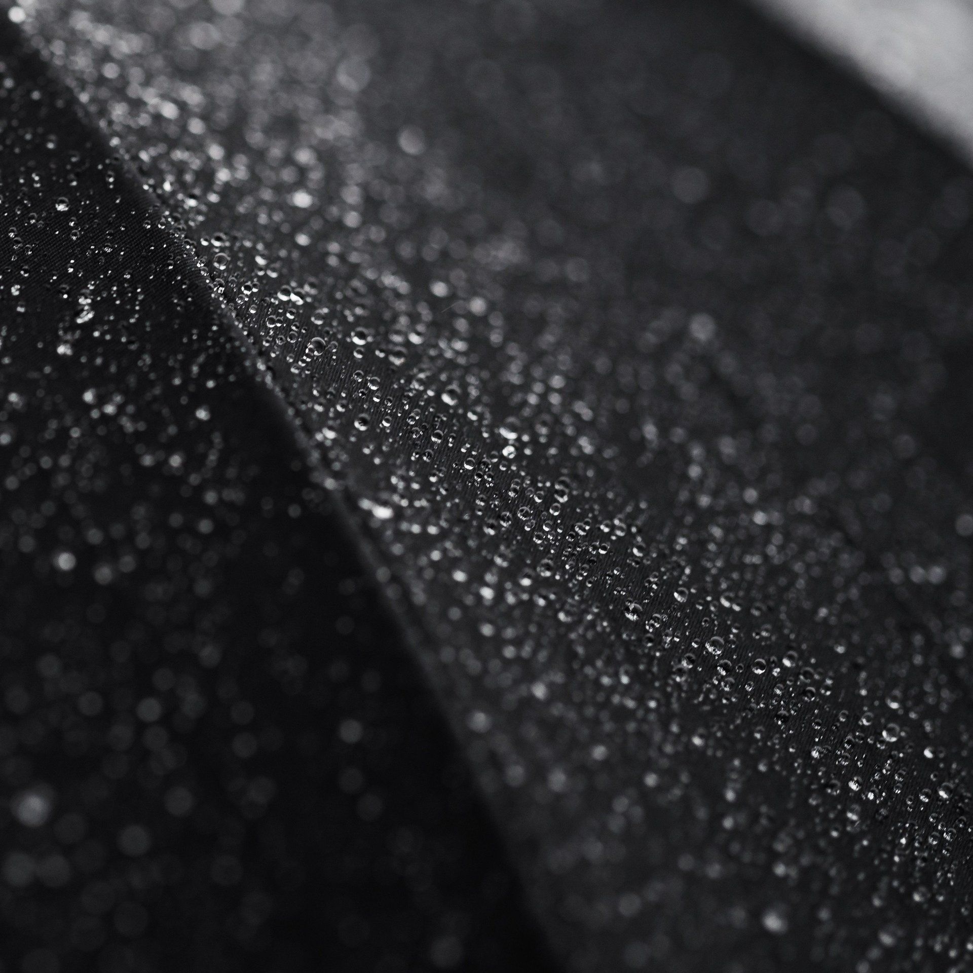 Black fabric with droplets of water on its surface.