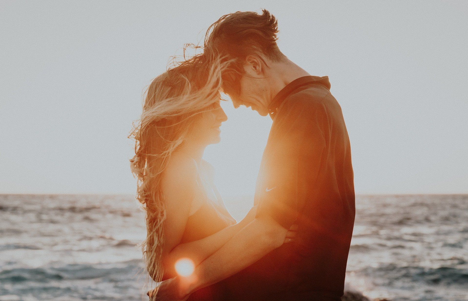 A man and a woman are hugging each other on the beach.