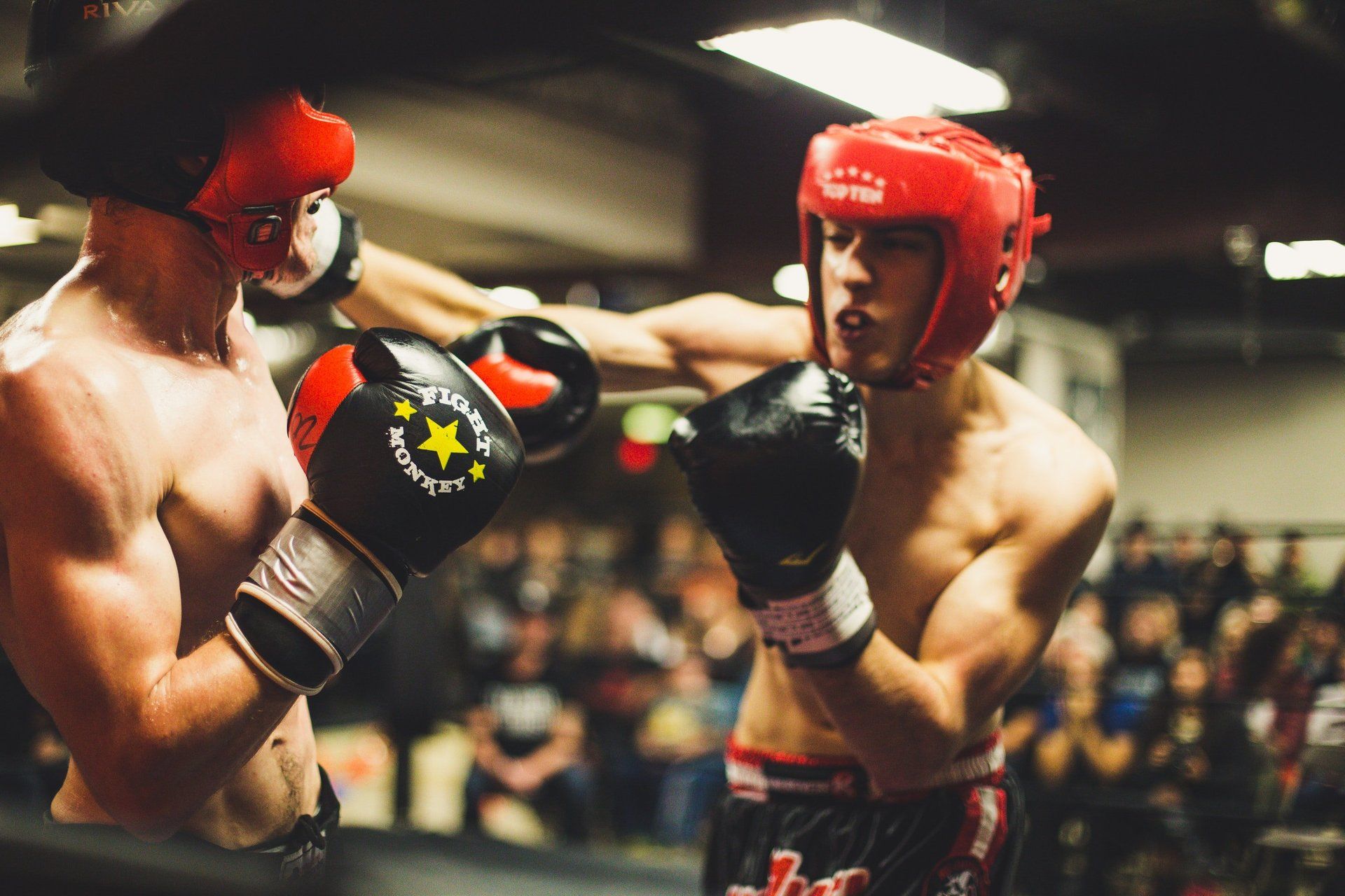 Two men are boxing in a ring with a crowd watching.