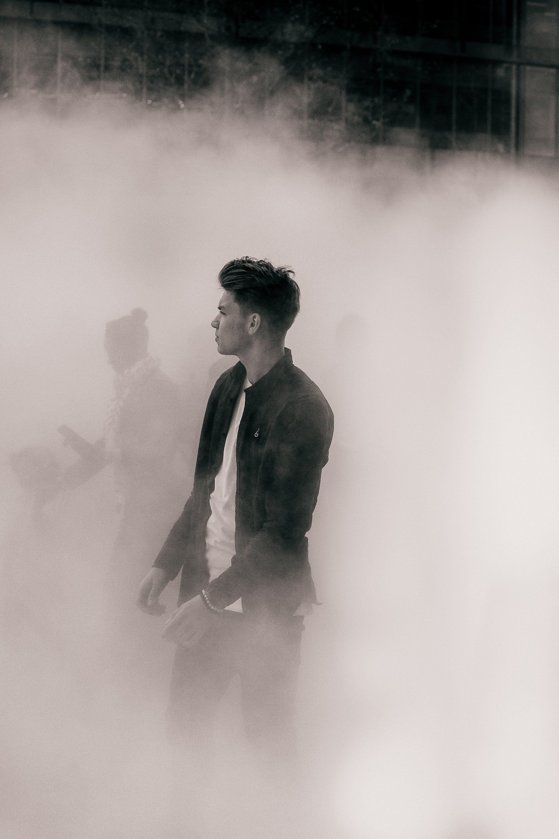 A man in a suit is standing in a foggy room.