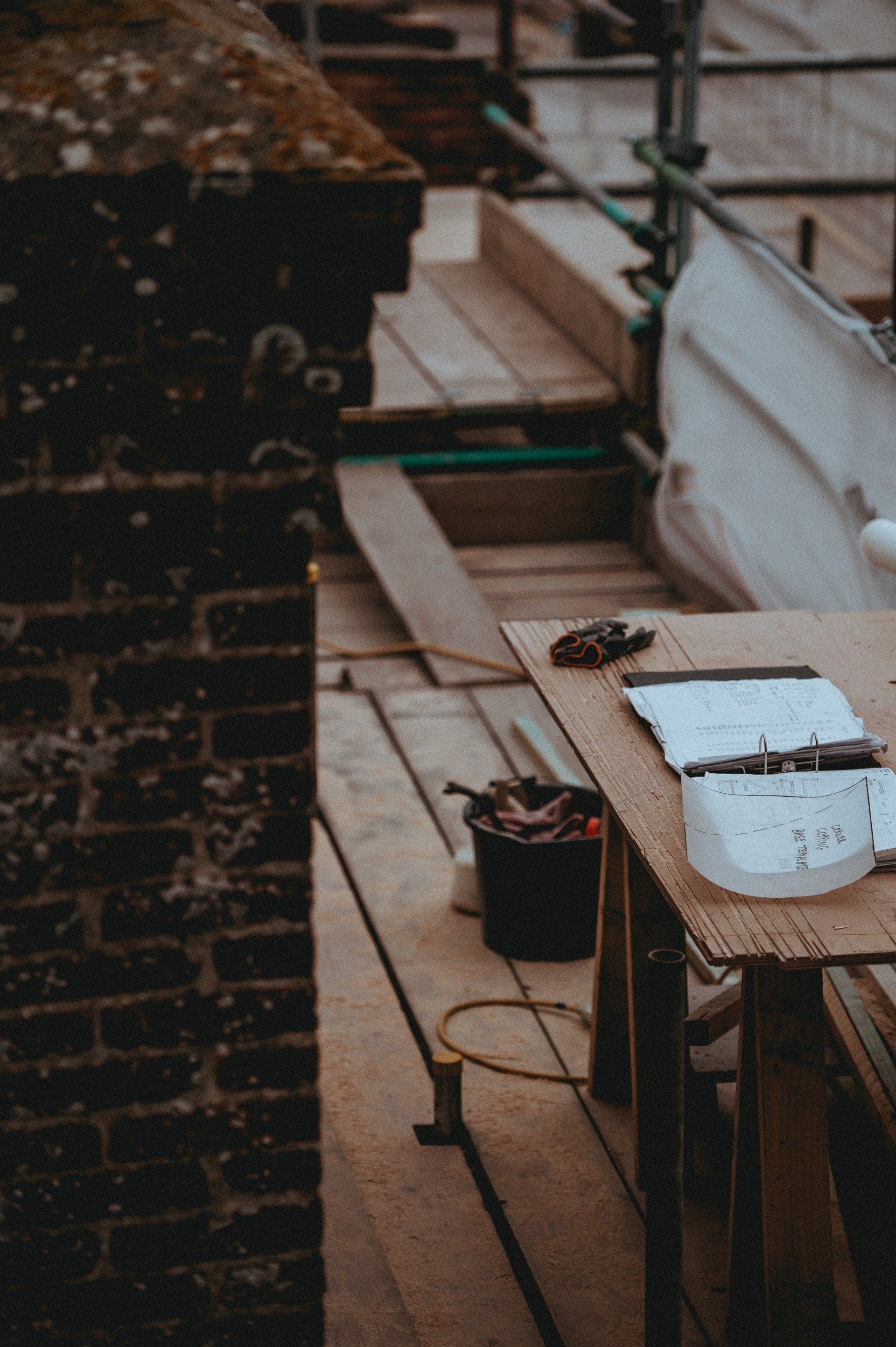 A wooden table with a bunch of tools on it in front of a brick wall.