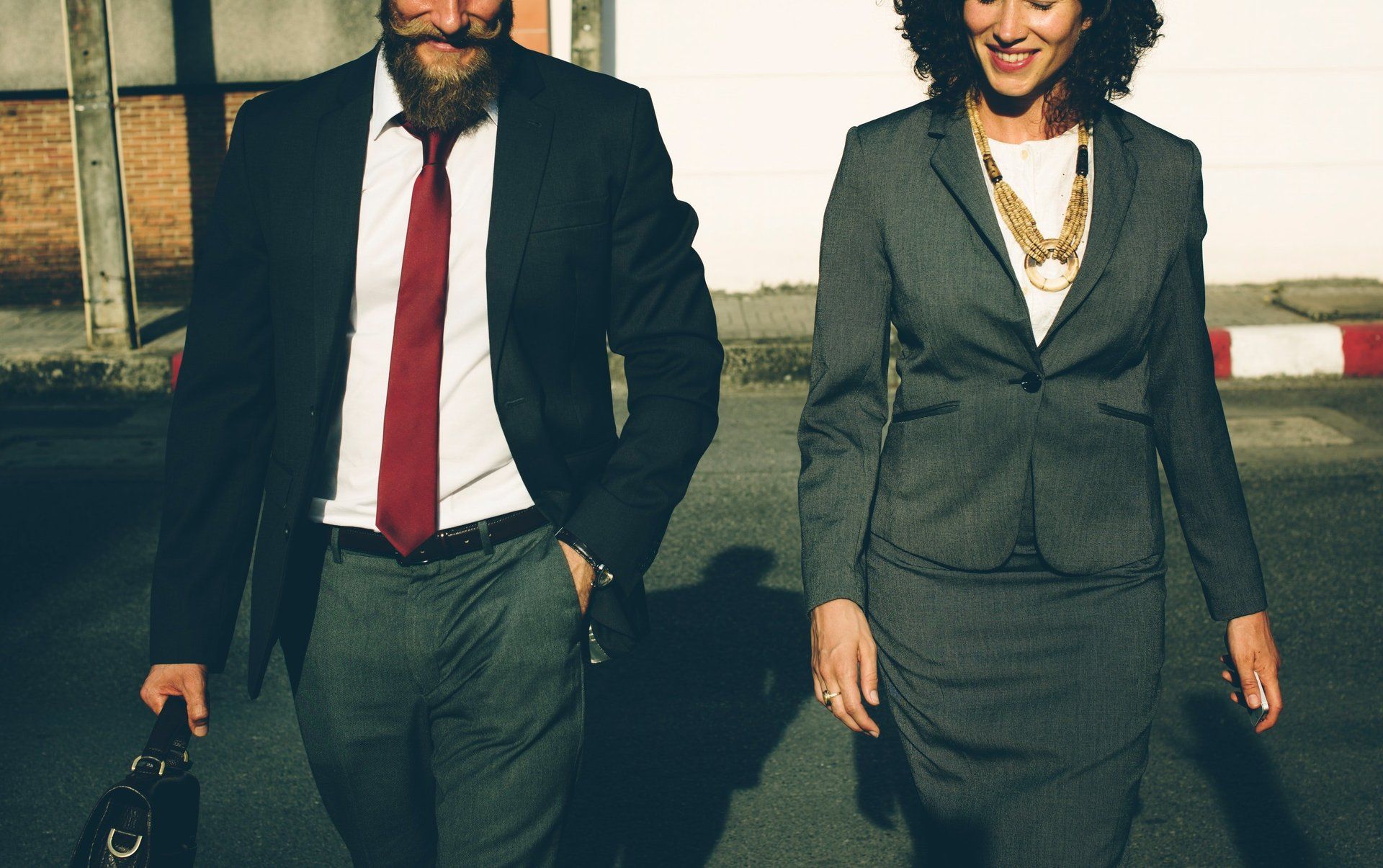 A man and a woman in business suits are walking down the street.
