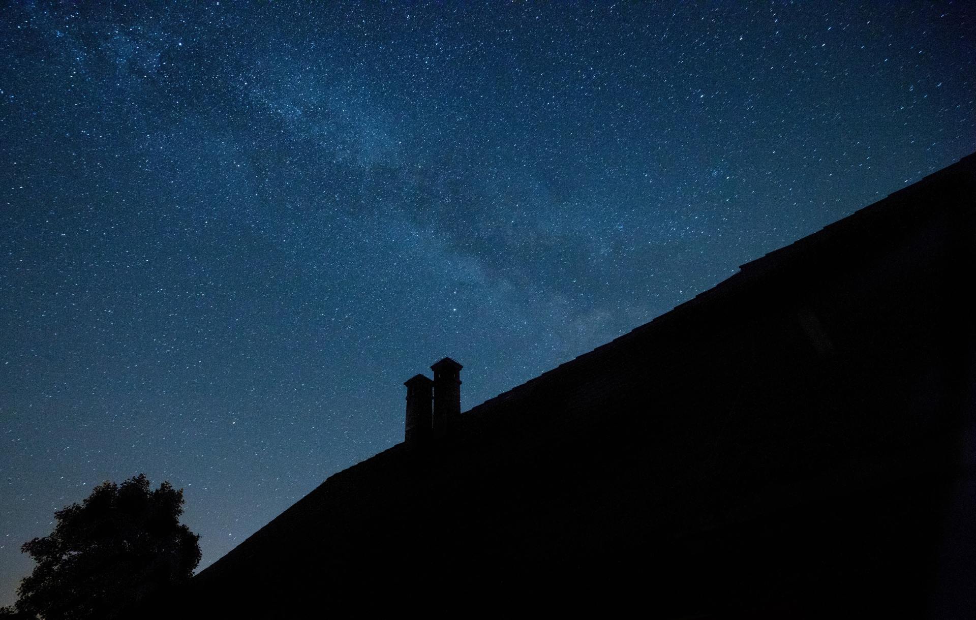 Night sky filled with stars above a silhouetted building.