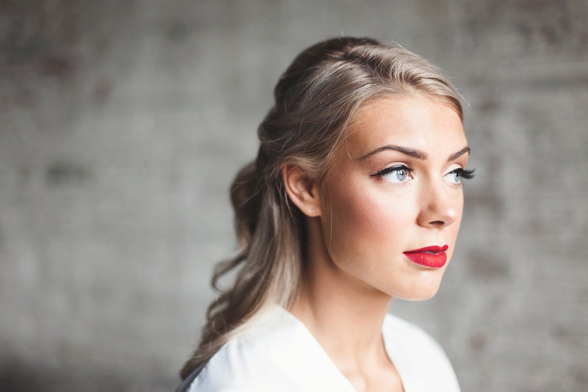 A close up of a woman wearing red lipstick and a white shirt.