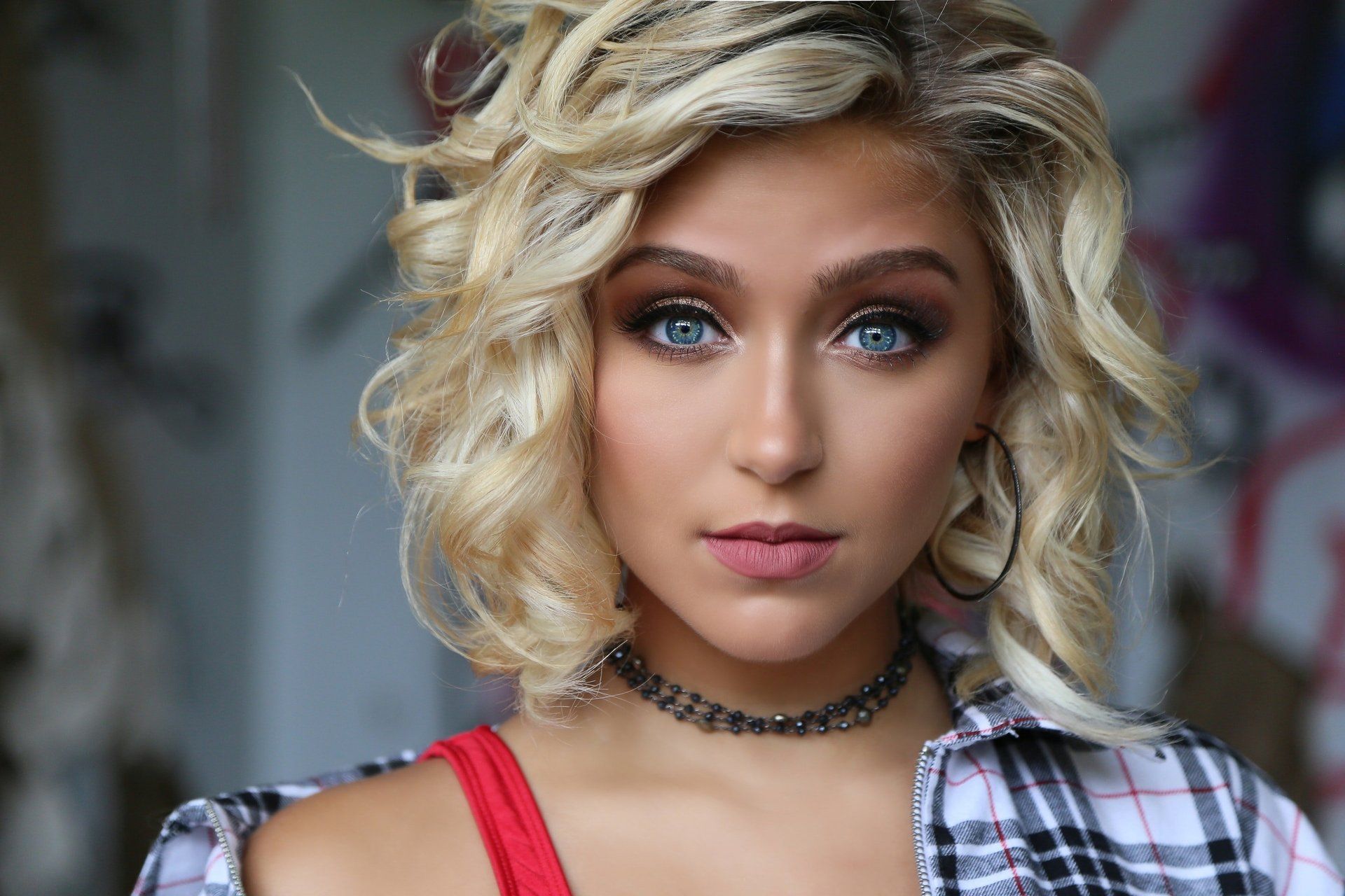 A close up of a woman wearing a choker and a plaid shirt.