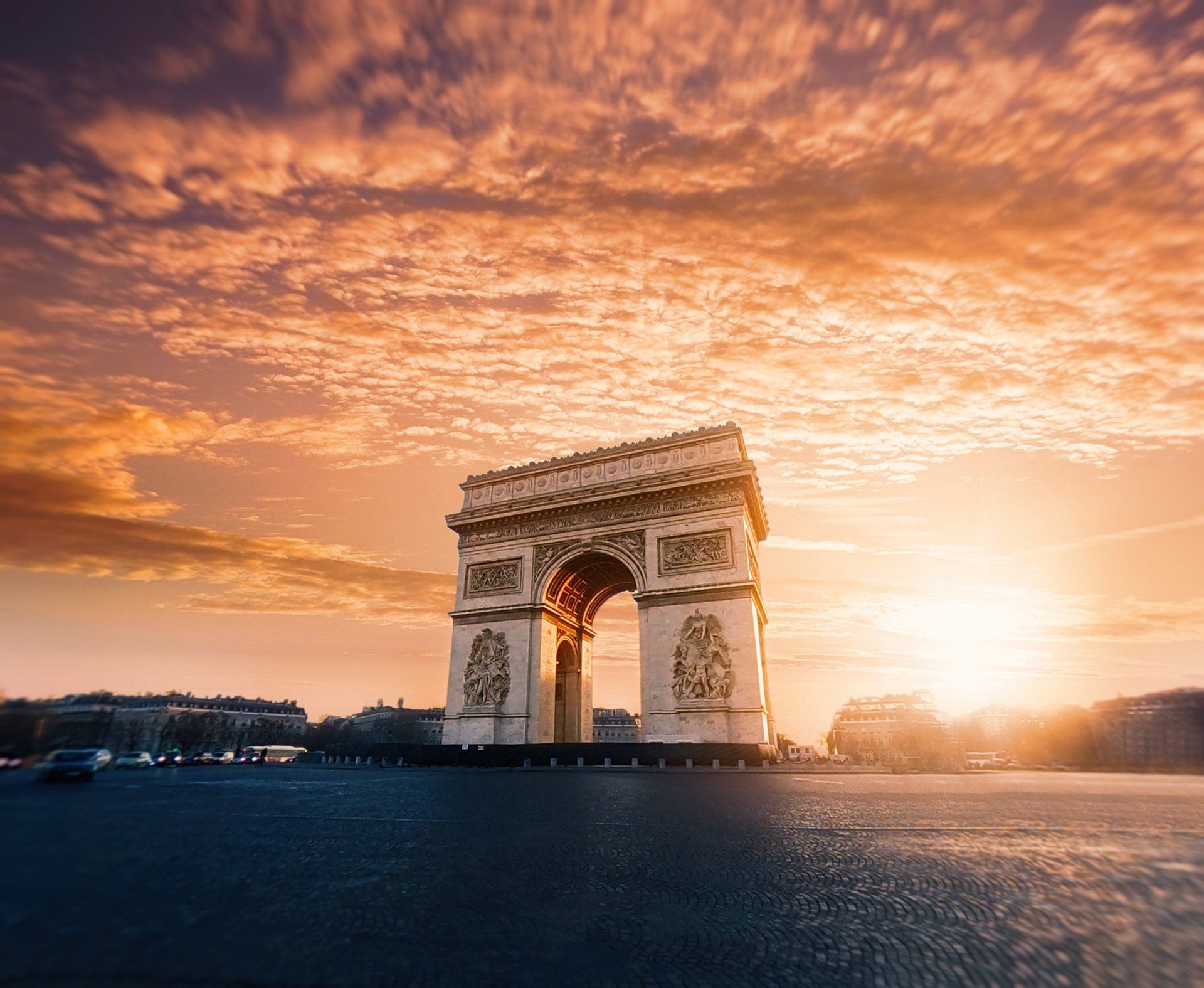 The triumphal arch in paris is surrounded by water at sunset.