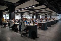 A group of people are sitting at desks in an office.
