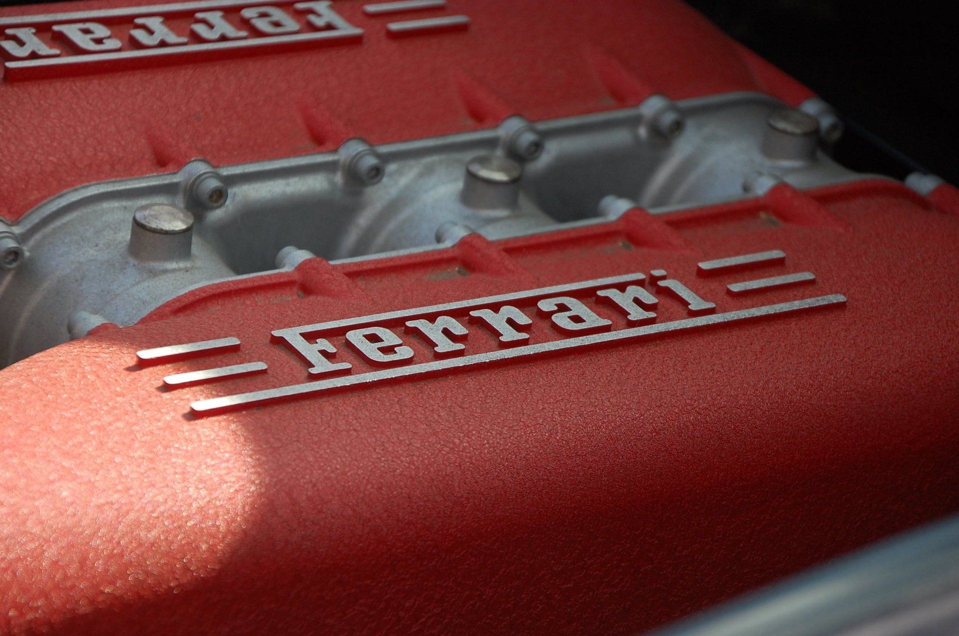 Nahaufnahme von roten Ferrari-Motorabdeckungen mit geprägtem Logo und silbernen Komponenten