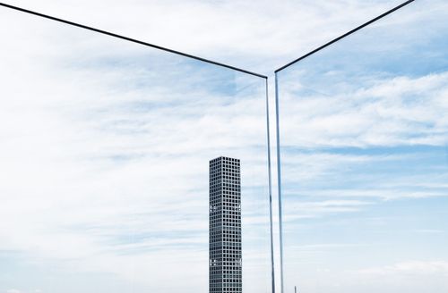 Hoher Wolkenkratzer, eingerahmt von schwarzen Linien vor einem bewölkten blauen Himmel.