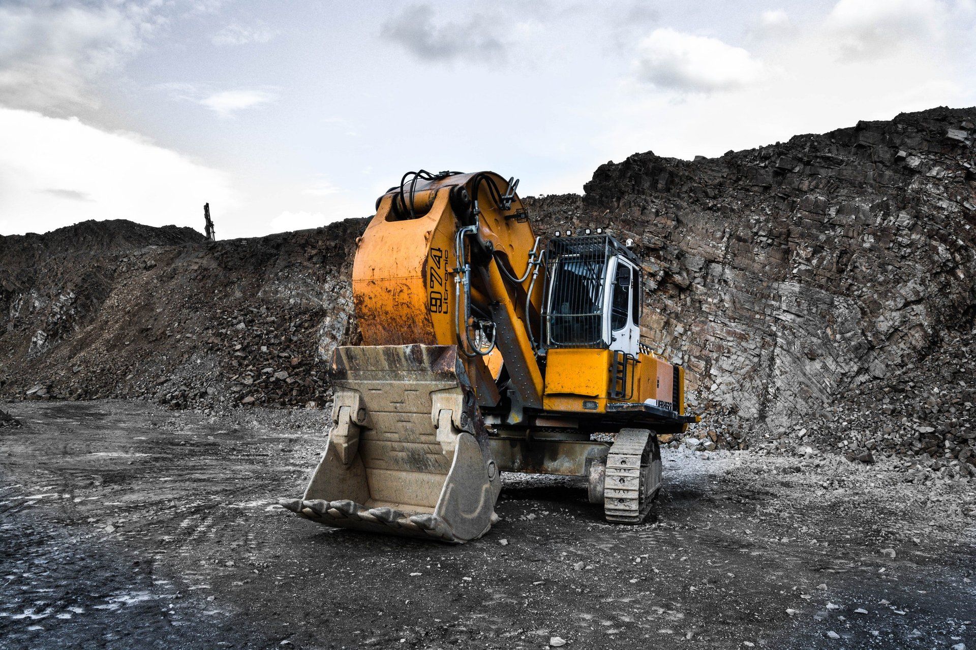 A yellow excavator is sitting on top of a pile of dirt.