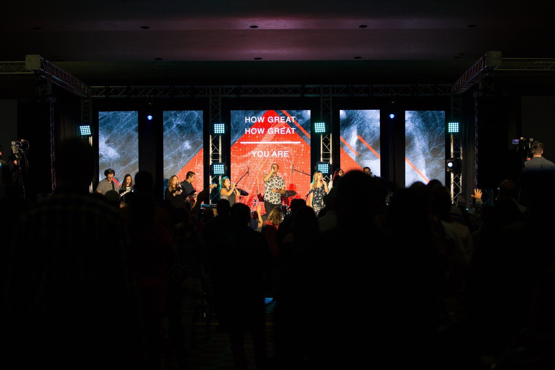 Crowd watching a live concert on a stage with red and blue lights
