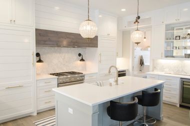 A kitchen with white cabinets , stainless steel appliances , and a large island.